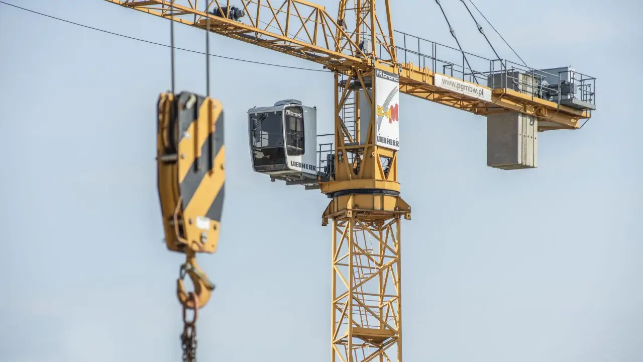 Kabina operatora dźwigu Liebherr, z której widać hak i łańcuchy, gotowa do pracy na budowie.
