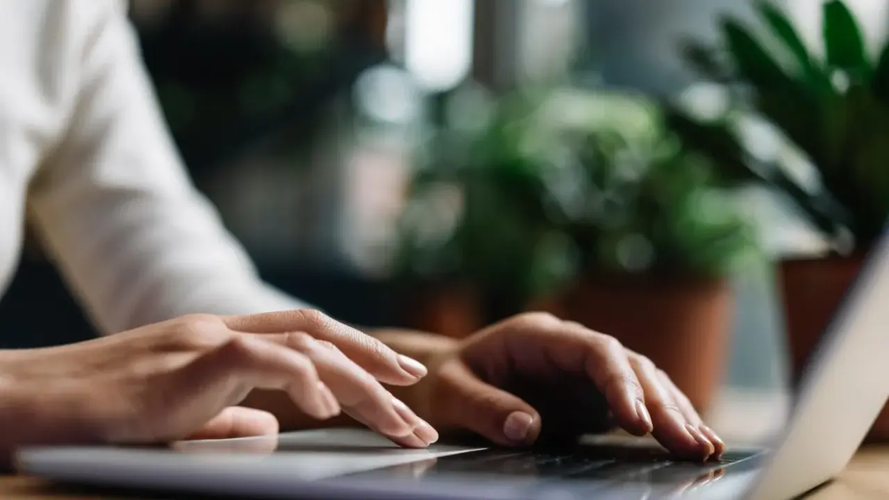 Dłonie piszą na laptopie, szukając możliwości pracy w Niemczech blisko granicy.