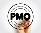 Ręka pisze markerem "PMO" w okręgu z napisem "PROJECT MANAGEMENT OFFICE". To symbol pmo stanowiska.