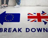 Strzałki z flagami UE i UK oraz napis "BREAK DOWN". Może to symbolizować trudności w uzyskaniu wizy pracowniczej UK po Brexicie.