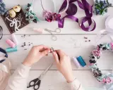 Ręce składają różańce, tworząc piękne ozdoby. Praca w domu z pasją i materiałami: wstążki, koraliki, kwiaty.