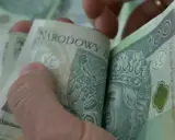Dłonie przeglądają stos banknotów 100 zł. Może to być kwota zasiłku rehabilitacyjnego, która pomoże w powrocie do zdrowia.