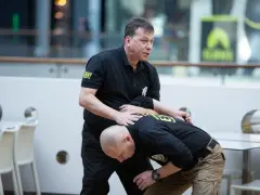 Instruktor pokazuje techniki samoobrony podczas kursu na ochroniarza.
