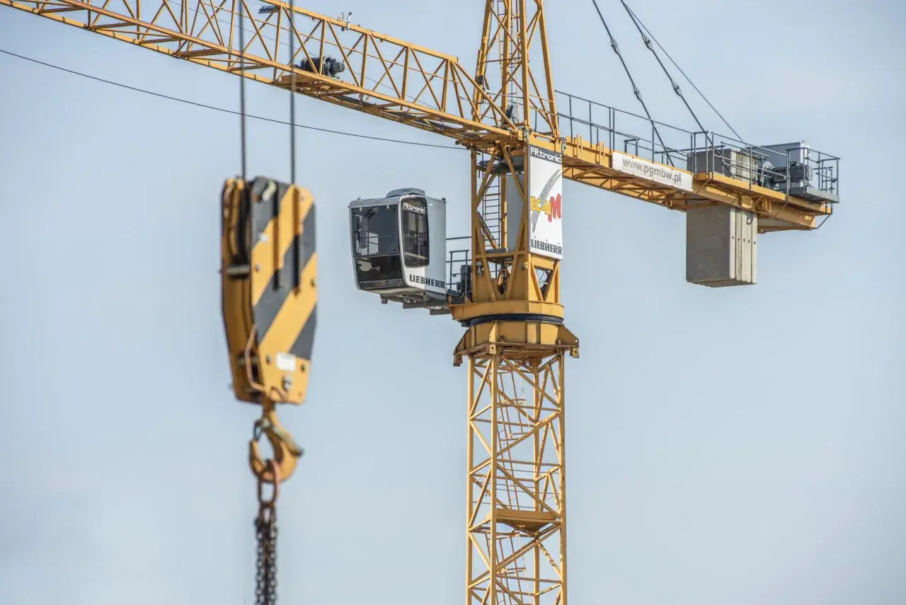 Kabina operatora dźwigu Liebherr, z której widać hak i łańcuchy, gotowa do pracy na budowie.