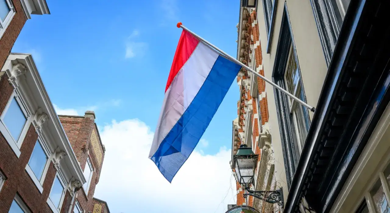 Holenderska flaga powiewa na tle błękitnego nieba. Marzenie o pracy w Holandii staje się rzeczywistością.