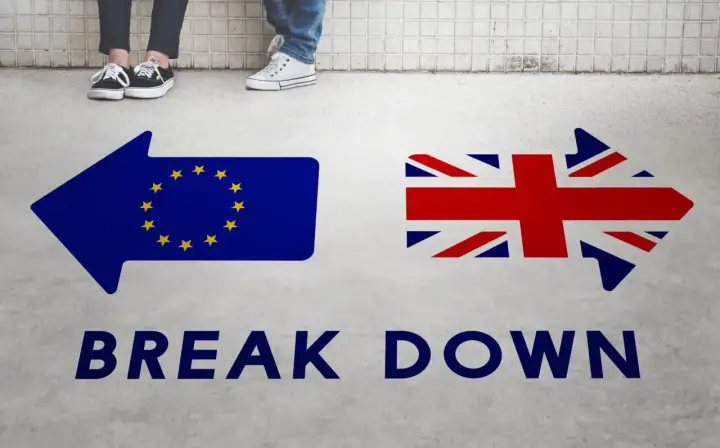 Strzałki z flagami UE i UK oraz napis "BREAK DOWN". Może to symbolizować trudności w uzyskaniu wizy pracowniczej UK po Brexicie.